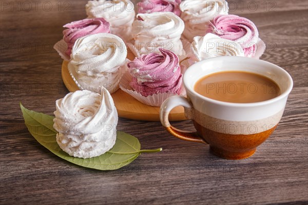 Pink and white homemade marshmallows (zephyr) on a round wooden board on a gray wooden background