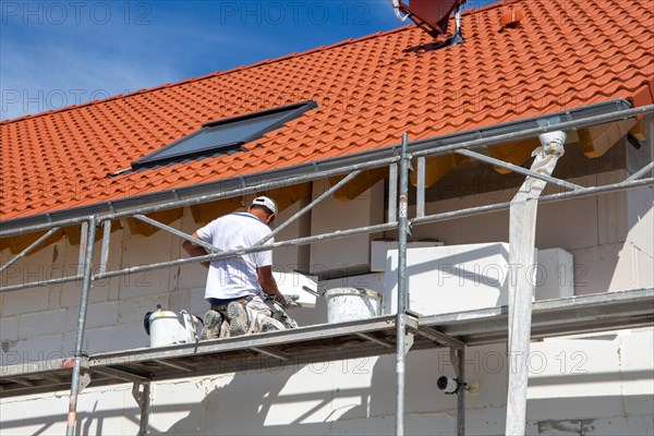 Construction workers insulate a house facade