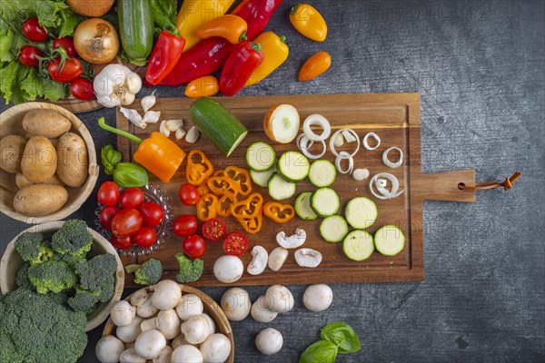 Various vegetables, peppers, tomatoes, onions, courgettes and broccoli arranged on a wooden board