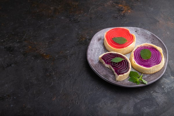 Sweet tartlets with jelly and milk cream on a black concrete background. Side view, copy space, close up