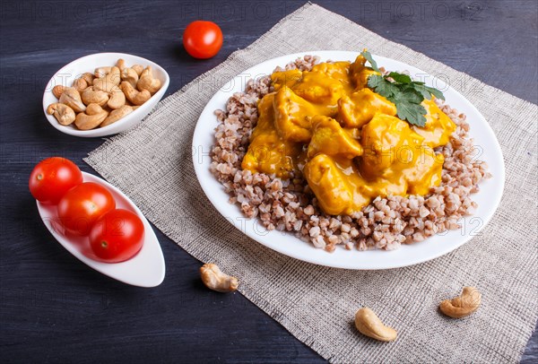 Buckwheat with chicken curry sauce with cashew on black wooden background. close up