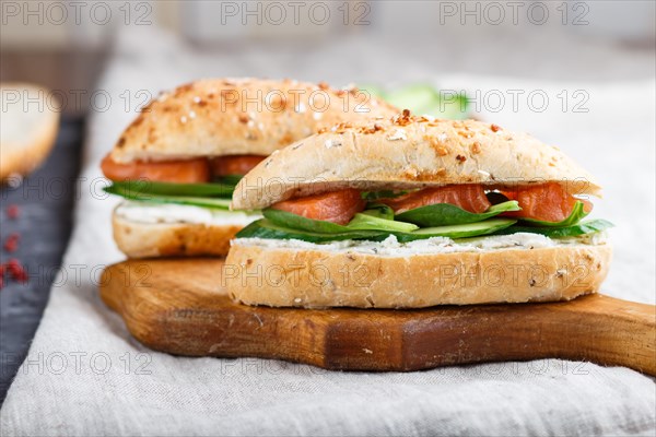 Smoked salmon sandwiches with cucumber and spinach on wooden board on a linen background. side view, close up