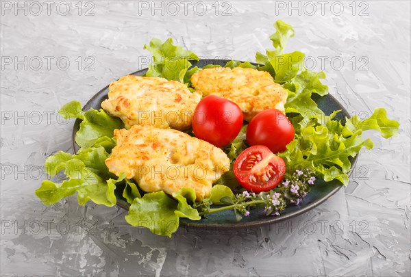 Minced chicken cutlets with lettuce, tomatoes and herbs on a gray concrete background. side view, close up