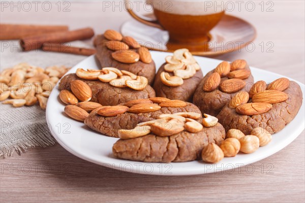 Small cakes potatoes with almonds and cashew nuts on a dessert plate. A cup of coffee, cinnamon, almonds, hazelnuts, cashew on a linen napkin. Still life