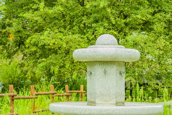 Large hand washing water fountain in a public park with lush green foliage in South Korea
