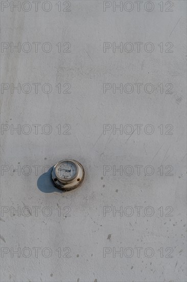 Thermometer mounted on outside wall of dirty white concrete wall. Temperature in photo incorrect in South Korea