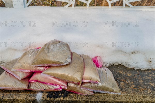 Small bags of sand on sidewalk beside fresh snowbank in South Korea