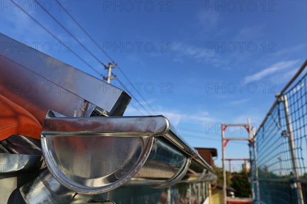 Close-up of a newly installed gutter in the course of tinsmith work on the roof covering