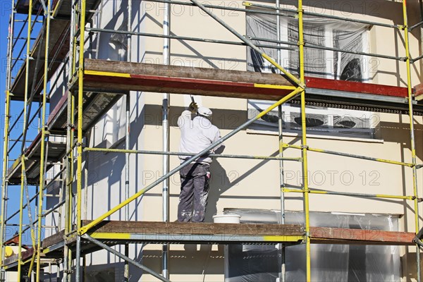 Painter painting the facade of a new residential building (Mutterstadt development area, Rhineland-Palatinate)