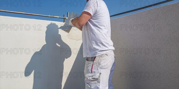 Plasterer plasters the facade of a new building