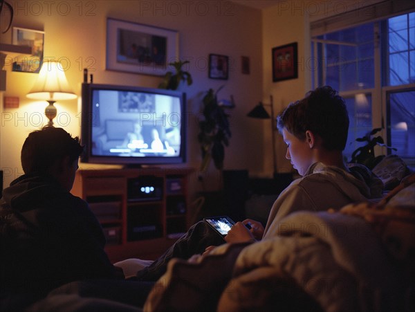 Two children are watching television in a cozy living room with warm lighting, boys and TV and smartphone, AI generated