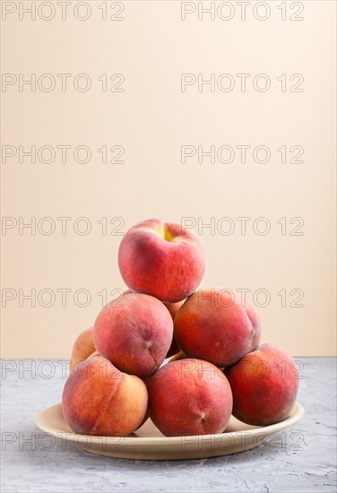 Fresh peaches on a plate on gray and orange pastel background. side view, close up