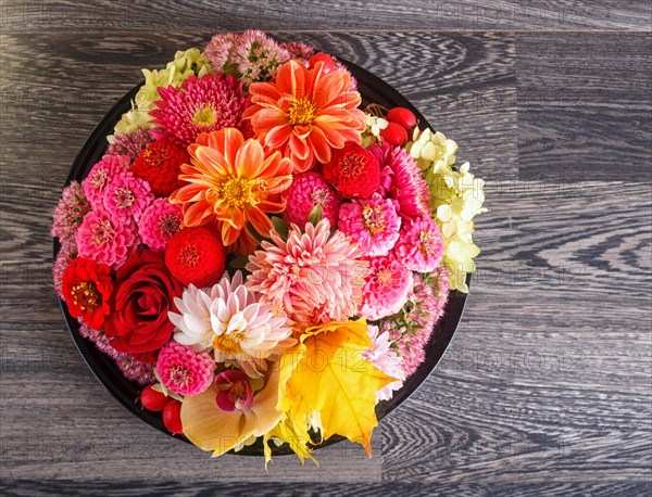 Floral arrangement of autumn flowers on a plate. dahlia, zinnia, rose, orchid, maple leaves