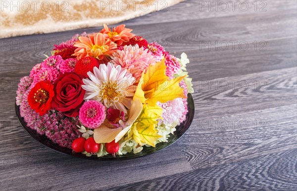 Floral arrangement of autumn flowers on a plate. dahlia, zinnia, rose, orchid, maple leaves. copy space