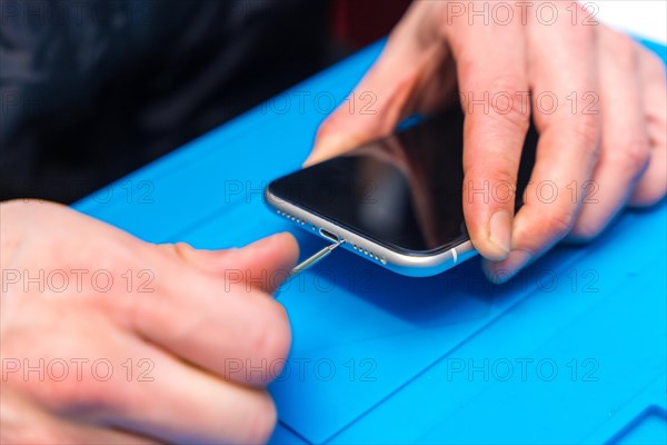 Close-up of a male technician using screwdriver to repair a mobile phone in a workshop