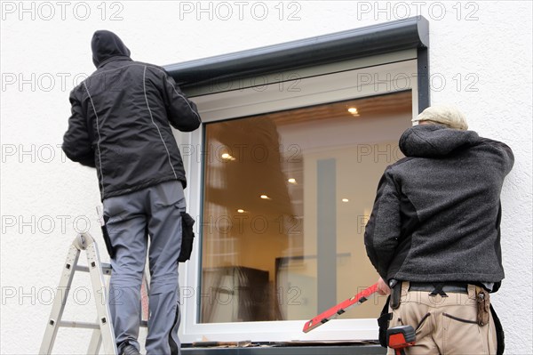 Craftsmen install a front-mounted roller shutter