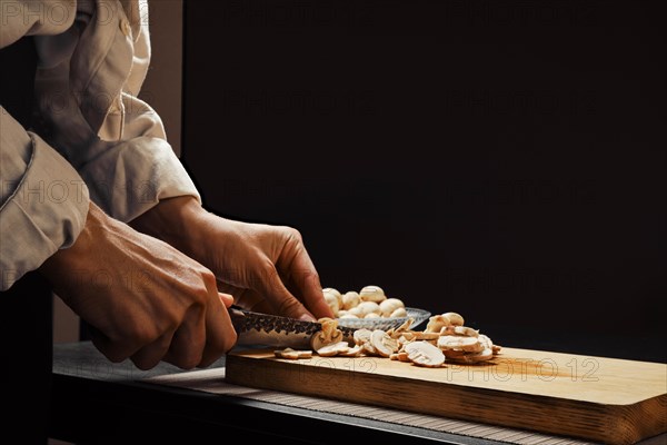 Hands of a woman cutting champignon mushrooms into thin slices