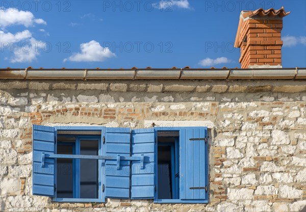 A rustic building with blue shutters under a clear blue sky with few clouds, Istria, Croatia, Europe