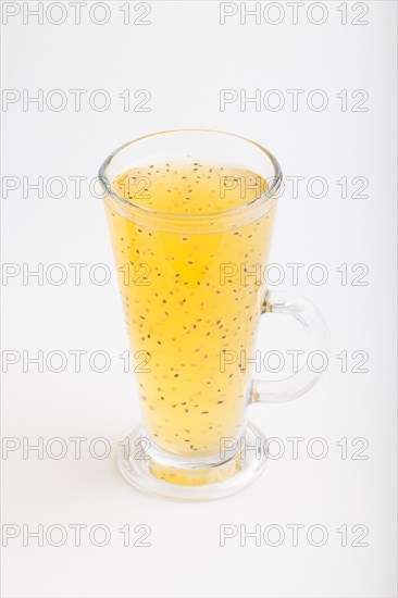 Glass of tangerine orange colored drink with basil seeds isolated on white background. Morninig, spring, healthy drink concept. Side view