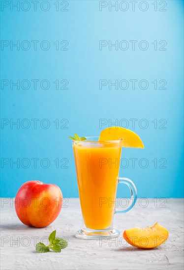 Glass of peach juice on a gray and blue background. Morninig, spring, healthy drink concept. Side view, copy space