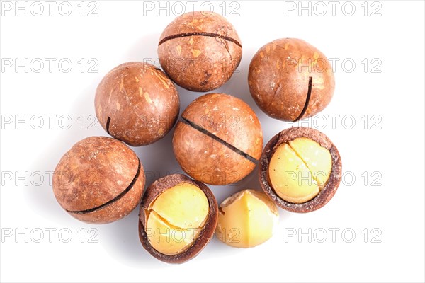 Pile of macadamia nuts with shell isolated on white background. top view