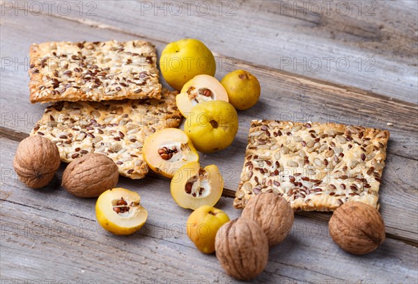 Biscuits with flax, sesame and sunflower seeds and yellow quince fruit on a rustic wooden background