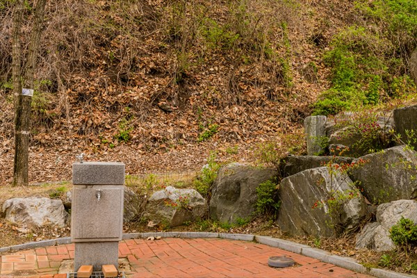 Water fountain in public park next to stack of large boulders in South Korea