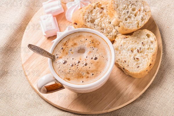 Sweet buns, meringues and coffee cup on a wooden board and linen tablecloth