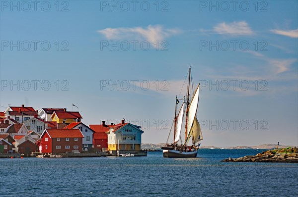 Sailing ship leaving a small harbour on the Swedish west coast, wooden houses, Kaeringon, Sweden, Europe