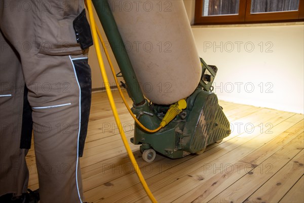 Craftsmen professionally sanding a plank floor