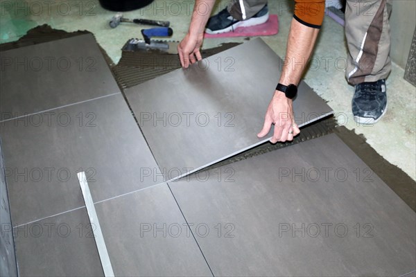 Tiler lays modern large floor tiles in a bathroom