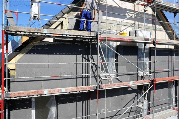 Construction workers insulate a house facade