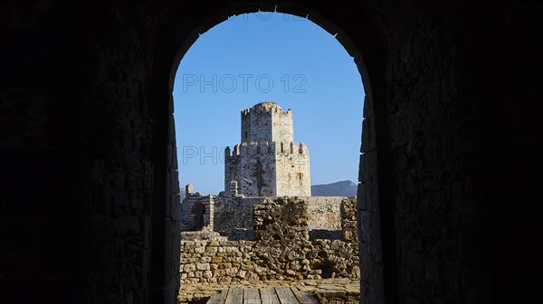 View through a stone arch to a ruin and the sea beyond, octagonal medieval tower. Islet of Bourtzi, sea fortress of Methoni, Peloponnese, Greece, Europe