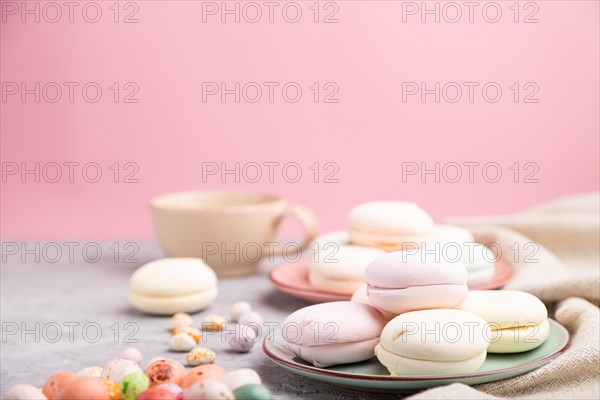 Colored zephyr or marshmallow with cup of coffee and dragees on a gray and pink background and linen textile. Side view, close up, selective focus, copy space