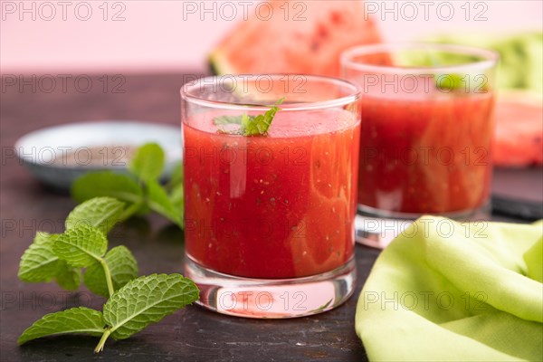 Watermelon juice with chia seeds and mint in glass on a black concrete background with green textile. Healthy drink concept. Side view, close up, selective focus