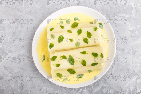 Cannelloni pasta with egg sauce, cream cheese and oregano leaves on a gray concrete background. top view, flat lay, close up