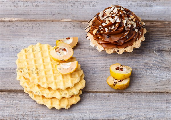 Sweet waffle and cake with cream on a rustic wooden background