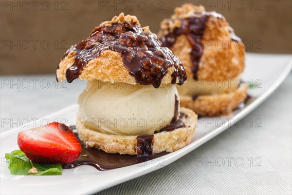 Fresh profiteroles with ice cream and chocolate on a white plate. selective focus. horizontal