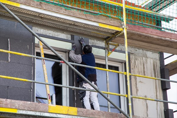 Construction workers insulate a house facade