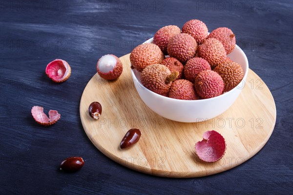 Lychee in a white plate on a black wooden background, close up