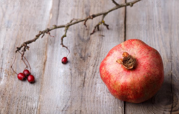 Ripe garnet with a branch on a rustic wooden background