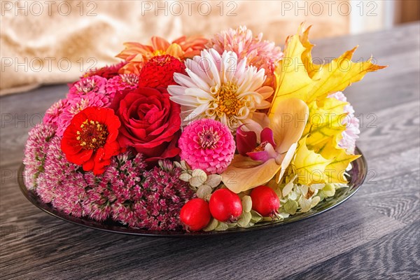 Floral arrangement of autumn flowers on a plate. dahlia, zinnia, rose, orchid, maple leaves