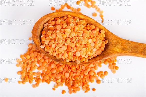 Pile of red lentils in a wooden spoon isolated on white background. Closeup