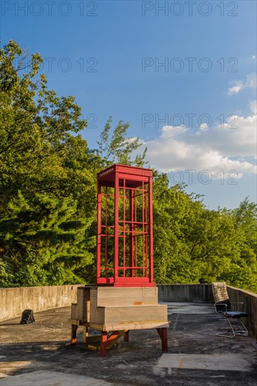 Red wooden telephone booth minus phone and without glass on roof of building on sunny day with blue skies in South Korea