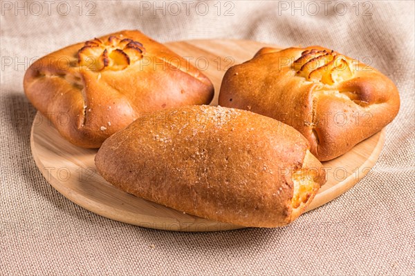 Sweet buns on a wooden board and linen tablecloth