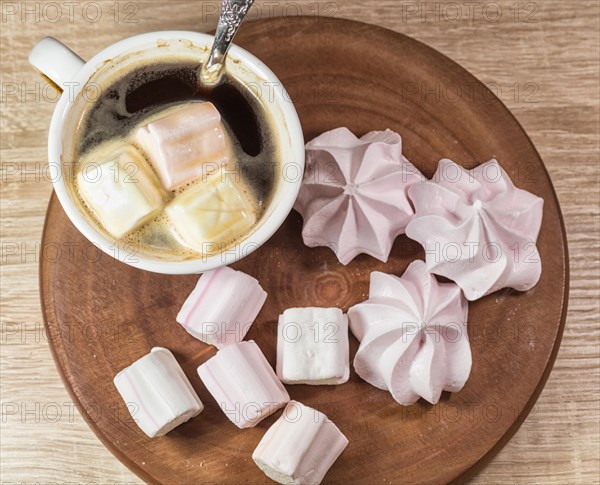 Chewing marshmallows, meringue and coffee cup on a wooden board and linen tablecloth