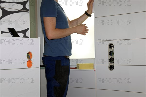 Tiler lays tiles on the wall