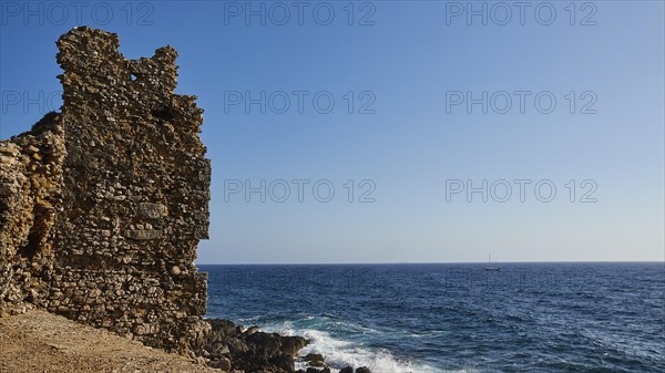 Forgotten ruin on the seashore with a sailing boat on the horizon, sea fortress Methoni, Peloponnese, Greece, Europe
