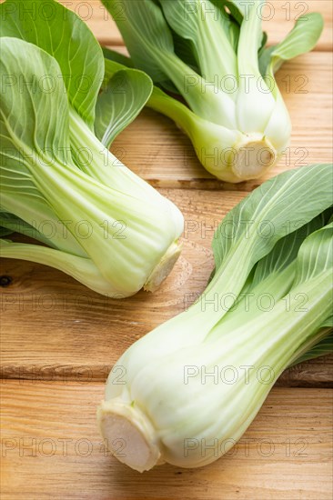 Fresh green bok choy or pac choi chinese cabbage on a brown wooden background. Side view, close up