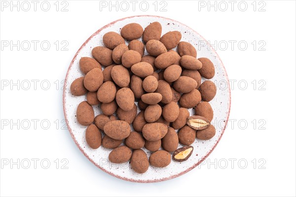 Almond in chocolate dragees on ceramic plate isolated on white background. Top view, close up